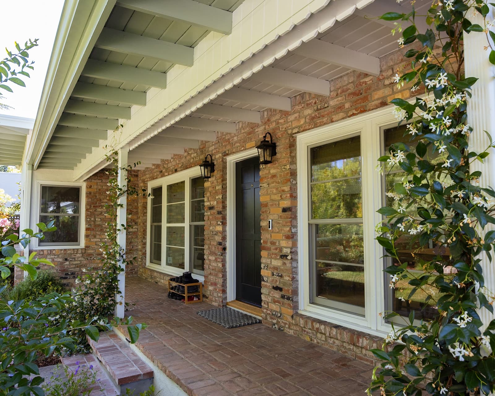 Front entry door framed by climbing jasmine on a restored brick facade