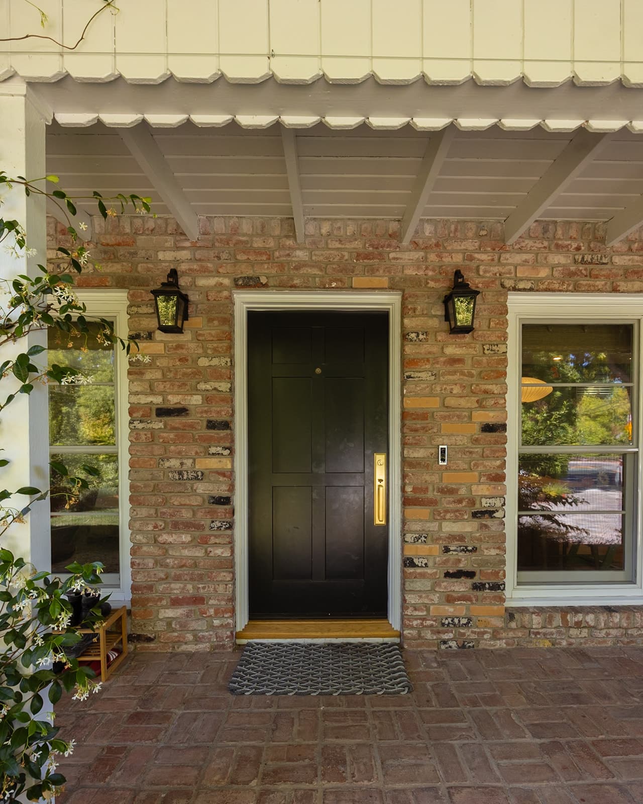Dark front door with a brass handle set into the home's original brick facade