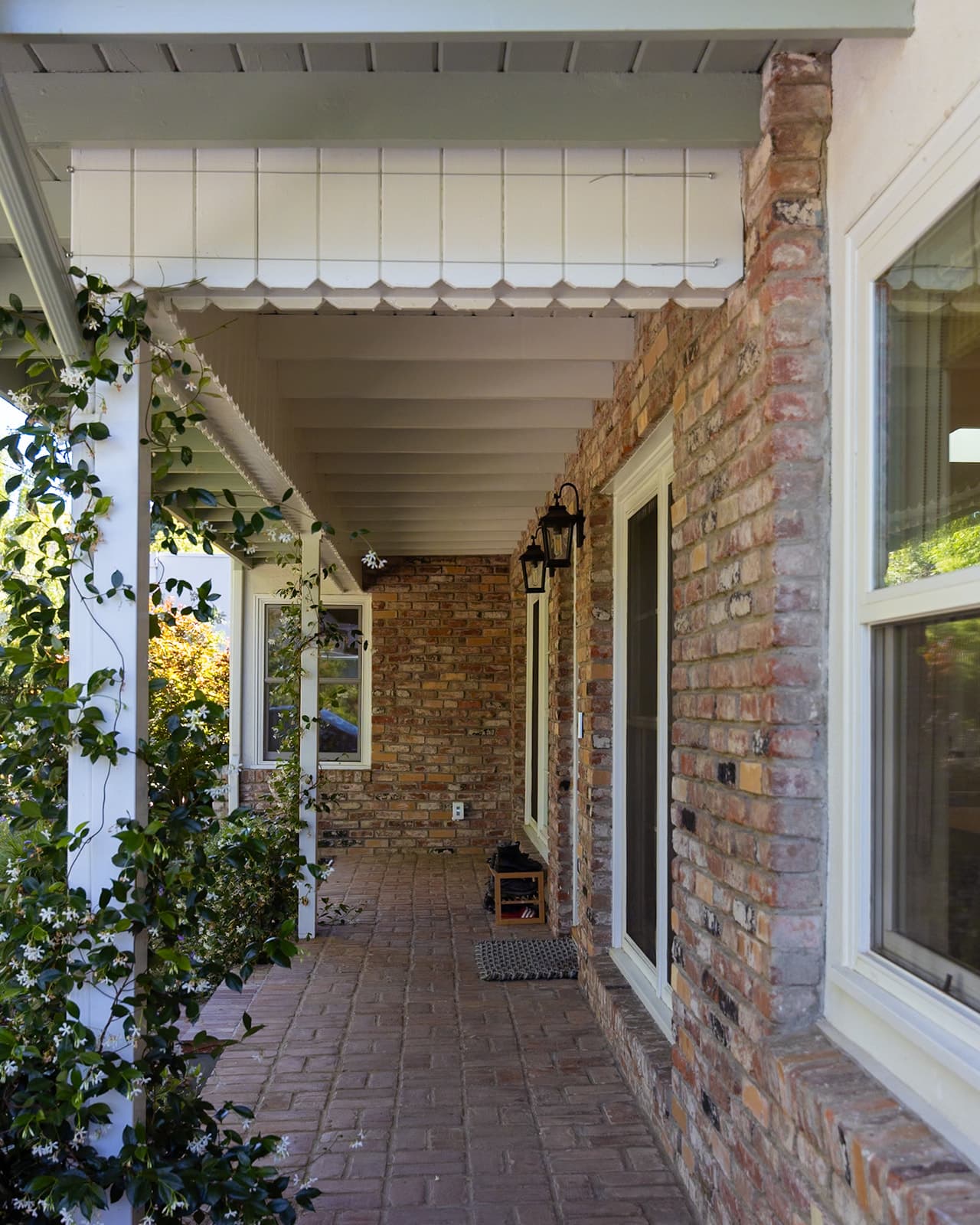 Brick porch walkway leading to the front door beneath a beadboard ceiling
