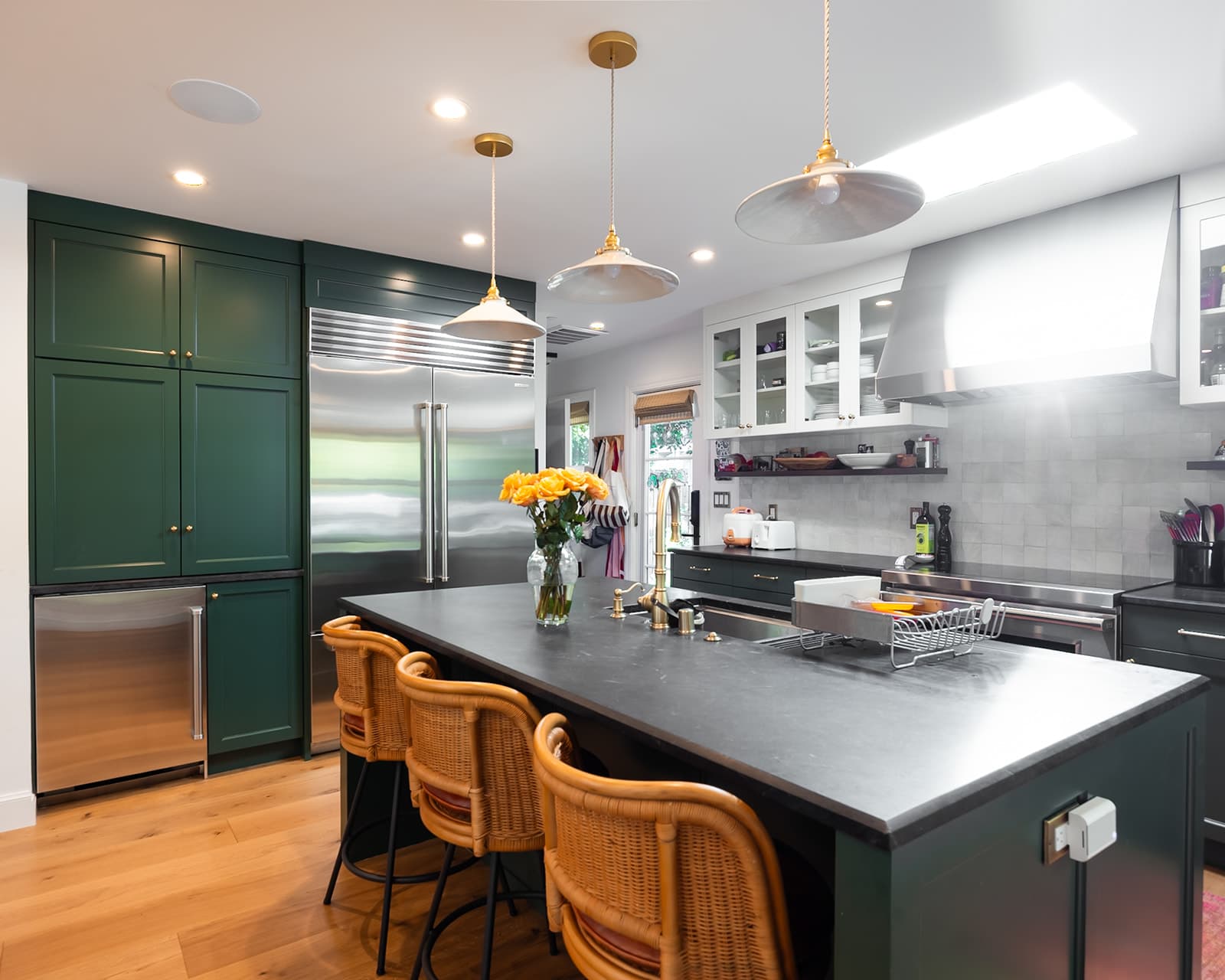 Remodeled kitchen with honed soapstone counters, deep green Wood-Mode cabinetry, and brass pendants