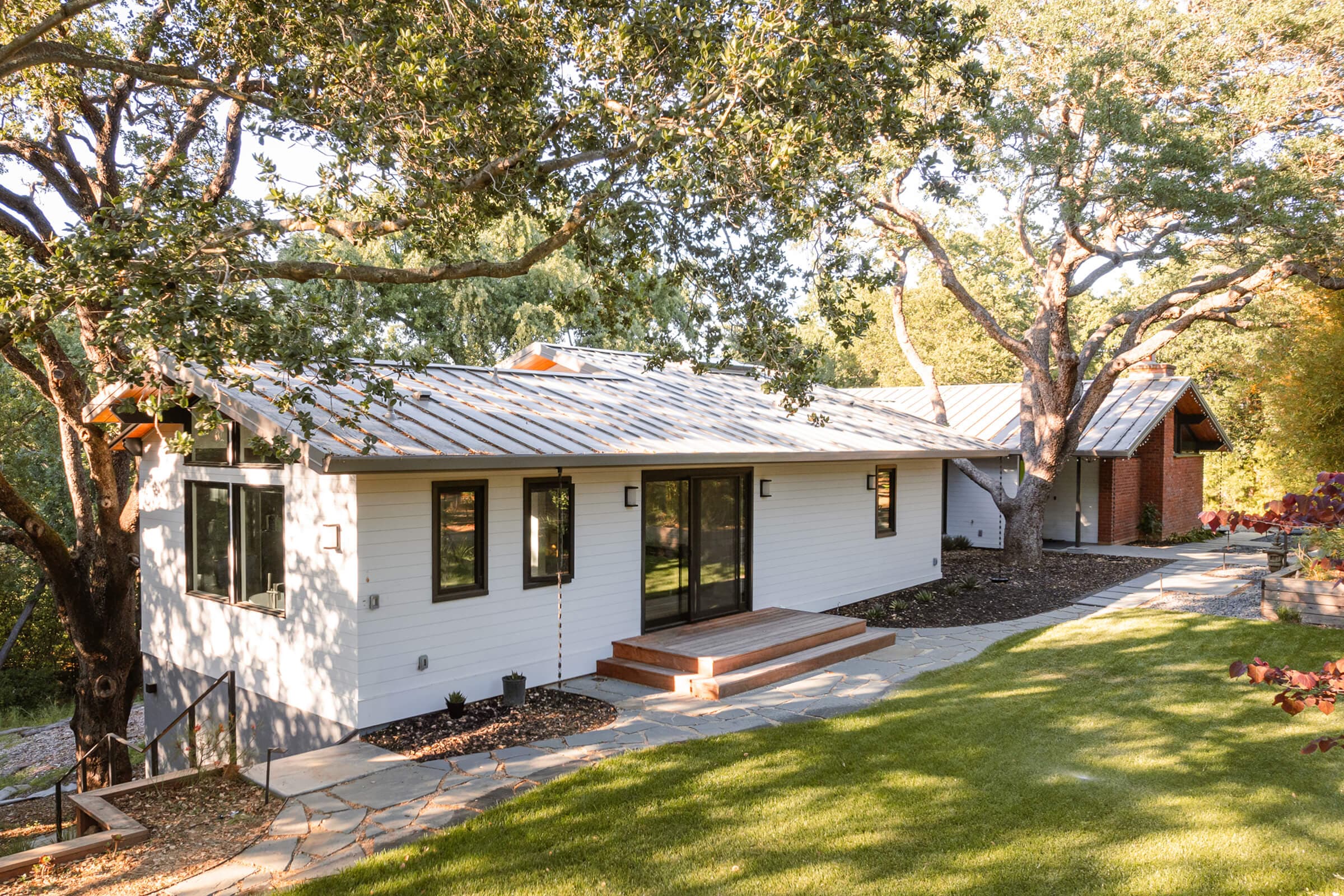 Side elevation with black-framed windows and a sliding door to the lawn