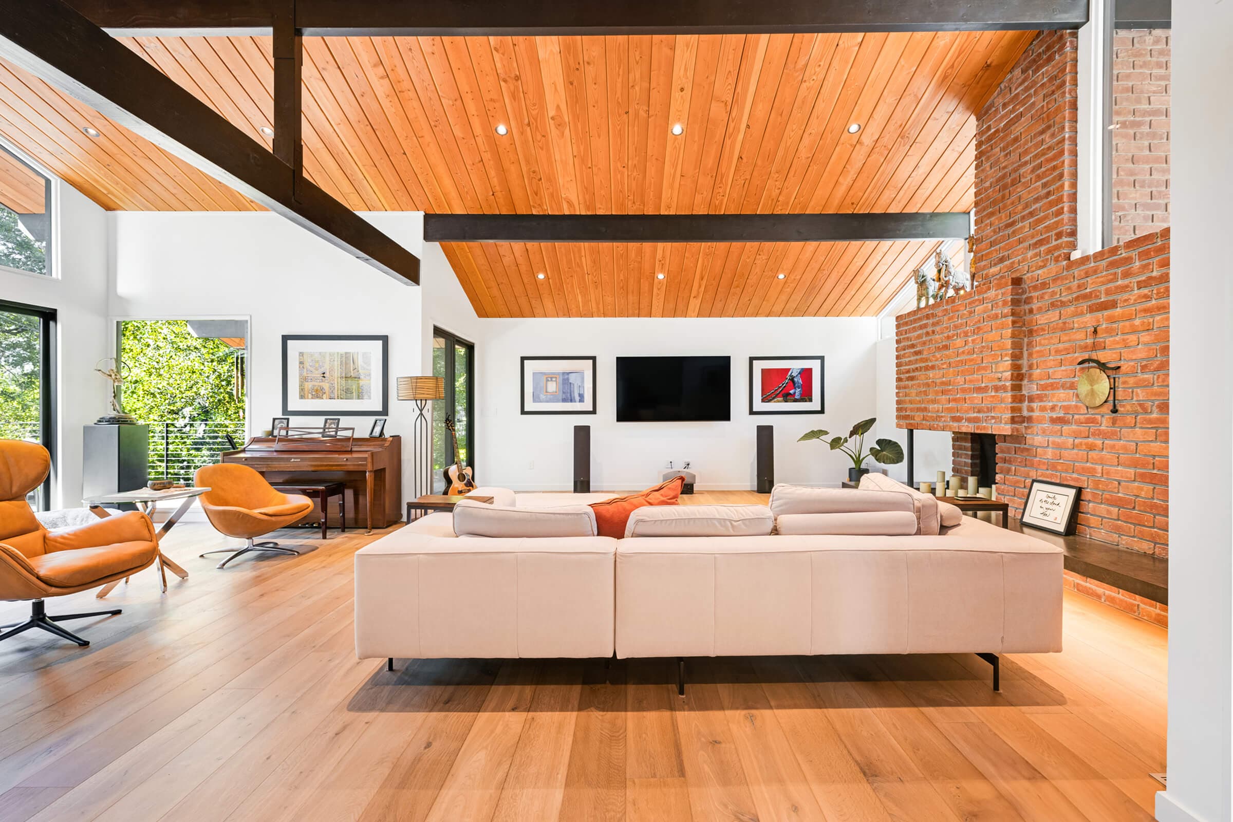 Living room with a tongue-and-groove wood ceiling, dark beams, and the original brick chimney